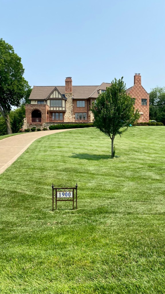 Photo of Aunt Arabell White Hemingway's house at the Northwest corner of 55th Street and State Line Road in Mission Hills, Kansas. The street number 1900 is visible on a large grassy yard in the photo as well as the large Tudor style house. The actual address is 1900 West 55th Street, Mission Hills, Kansas