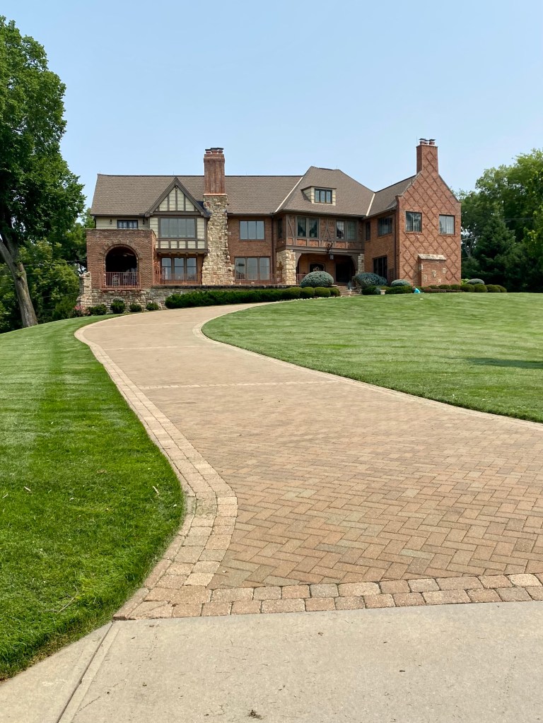 Photo of Aunt Arabell's house in Mission Hills, Kansas, where Hemingway and his wife Pauline stayed during Pauline's pregnancy with their son Patrick in 1928. Photo shows a large Tudor style house and the long driveway leading up to it